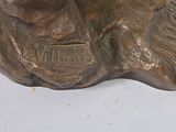 bronze statue of a man with a hat on his head sitting on a rock