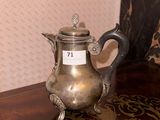 a silver tea pot sitting on a table with a name tag on it