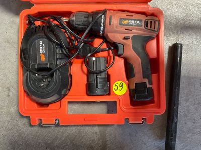 une perceuse sans fil dans une boîte à outils avec un chargeur