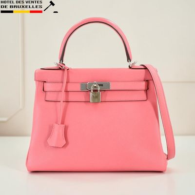 un sac à main rose posé sur une table près d'un mur blanc
