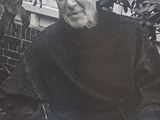 black and white photograph of an old man sitting on a bench in a garden