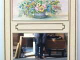un homme debout devant un miroir sur lequel est représenté un tableau