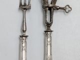 two forks and a knife on a white surface