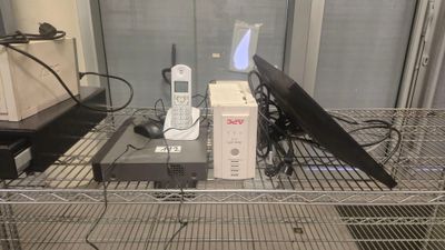 un ordinateur portable et un téléphone portable posés sur une étagère en fil métallique