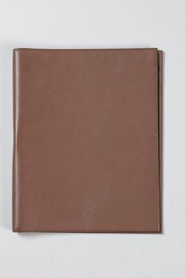 a brown leather notebook on a white surface with a white background