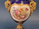 a blue vase with a gold handle and flowers on it