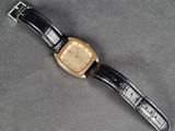 a close up of a watch on a table with a black strap