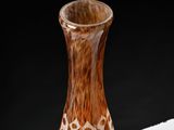 a brown and white vase sitting on a white table