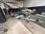 une petite voiture verte sur une remorque dans un garage