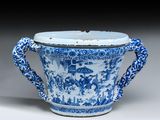 une tasse bleue et blanche à anses, ornée d'une scène représentant un village