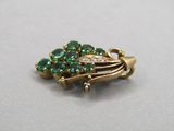 an image of a gold brooch with green stones on it