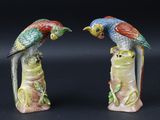 deux figurines représentant des perroquets perchés sur une souche d'arbre