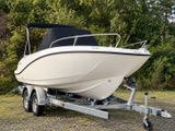 a white boat on a trailer parked in the grass
