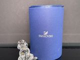 un petit ours en verre posé à côté d'un récipient bleu