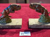 two statues of fish on a marble base on a red table