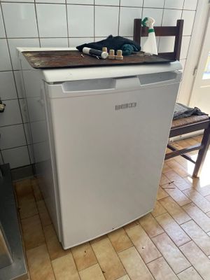 un petit réfrigérateur blanc dans une cuisine au sol carrelé