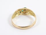 a close up of a gold ring with a green stone