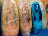 trois kayaks emballés dans du plastique, posés sur une table bleue