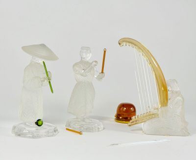 three figurines of people with musical instruments on a white surface