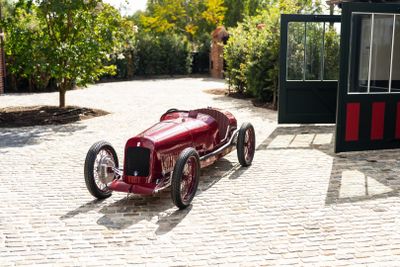 a red car that is sitting on a cobblestone road