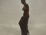 a bronze statue of a woman sitting on a rock