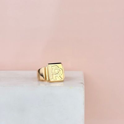 une bague en or sur laquelle figure la lettre « r »