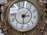 a gold clock with a white face and numbers on it