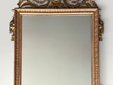 un miroir au cadre doré ouvragé accroché au mur, à côté d'un mur blanc