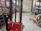 un chariot élévateur rouge dans un entrepôt rempli de rayonnages