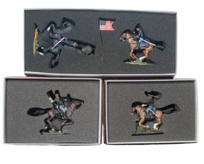 three figurines of a man riding a horse with a flag in the background