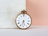a gold pocket watch sitting on top of a marble block