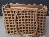un sac tressé muni d'une poignée en bois, posé sur une table