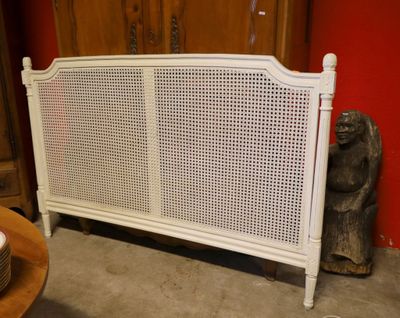 une tête de lit en rotin blanc posée sur une table dans une chambre