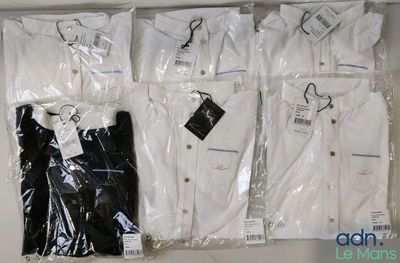 four shirts that are wrapped in plastic bags on a shelf