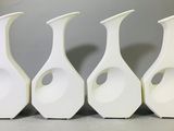 quatre vases blancs sont alignés sur une table
