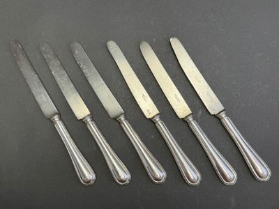 a set of five silverplated knives and a knife on a table