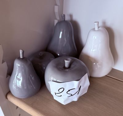 trois pommes et deux poires posées sur une étagère