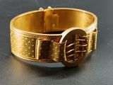 a close up of a gold bracelet with a buckle on it