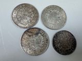 quatre pièces d'argent empilées les unes sur les autres sur une surface blanche
