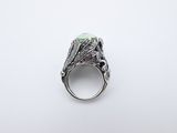 a close up of a ring with a green stone on it