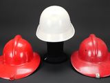 three red and white hard hats sitting on top of a black table