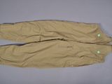 une photo d'un pantalon beige posé sur une surface grise