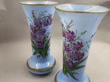 deux vases avec des fleurs peintes dessus, posés sur une table