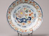 une assiette ornée d'un motif floral, posée sur un socle
