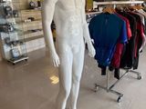 a male mannequin in a store with many shirts on display