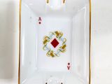 a white ashtray with gold trim and a red diamond in the center