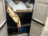 an open door to a storage unit with a bucket and other items in it