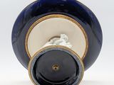 a blue and white vase with a gold rim on it
