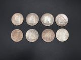 a group of six silver coins on a black surface