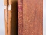 un vieux livre ouvert, posé sur une table à côté d'un autre livre